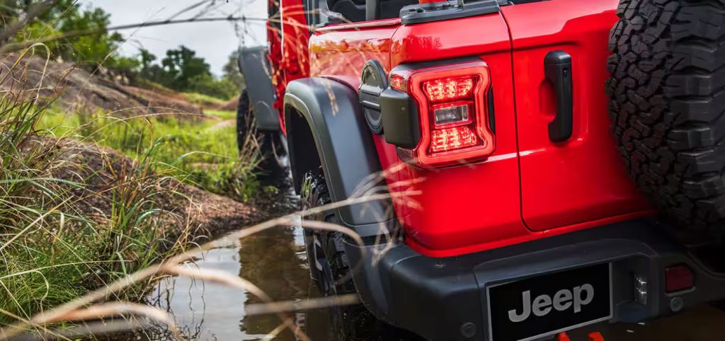 red jeep wrangler driving through the mud