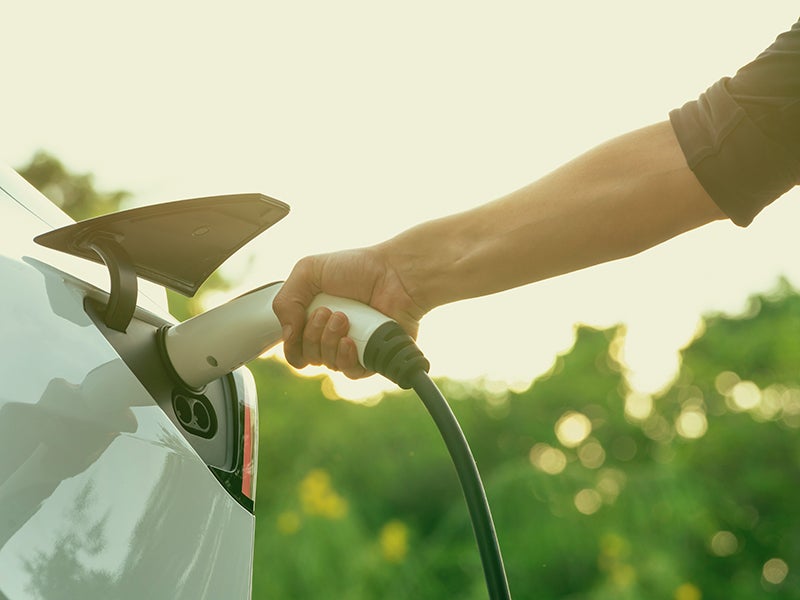 Hand holding an EV charger plugged into a car